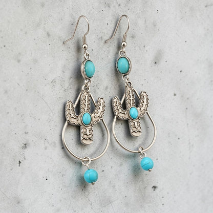 Fury Jewelry & Design silver-tone cactus drop earrings with turquoise stones and hook backings on a grey background.