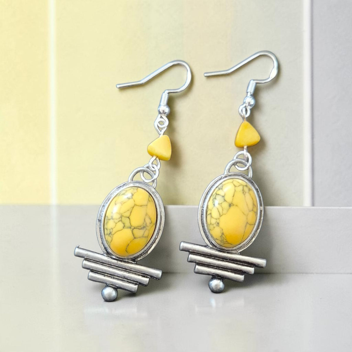 Fury Jewelry & Design yellow turquoise oval drop earrings with silver-tone geometric accents and triangular stones.